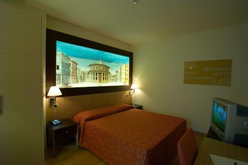 カンピ・ビゼンツィオにあるウェスト フローレンスのベッド付きの客室で、壁には絵画が飾られています。