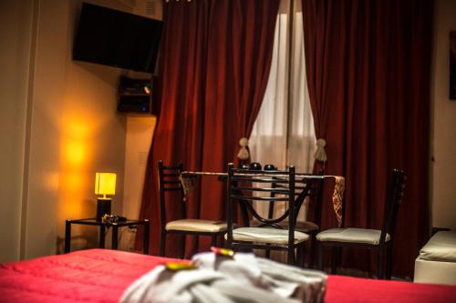 布宜諾斯艾利斯的住宿－Esmeralda 625 6º，一间卧室配有两把椅子和一张红色窗帘的床