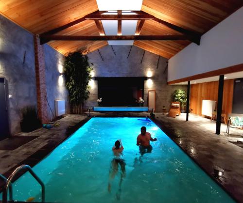 a man and a child swimming in a swimming pool at Vakantieverblijf Alfzotmolen in Beernem