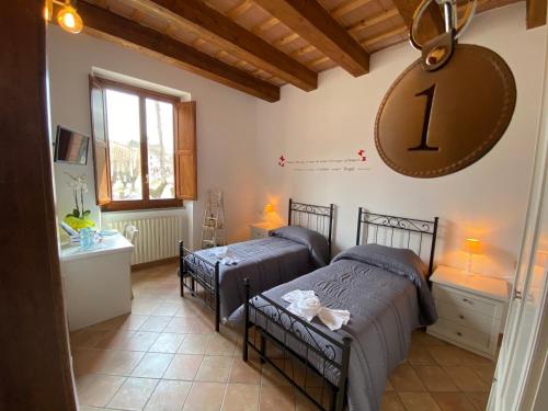 um quarto com duas camas e um relógio na parede em Locanda della Pieve em Pievebovigliana