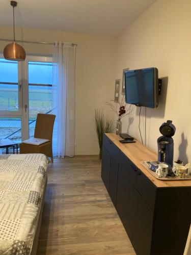 Siefersheim的住宿－Doppelzimmer mit Ausblick，一间卧室配有一张床,梳妆台上配有电视