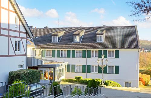 a large white building with green trim at Waldhotel Eskeshof in Wuppertal