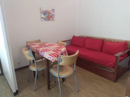 sala de estar con sofá rojo, mesa y sillas en DPTO VICTORIA II en Mar del Plata