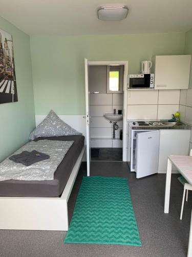 ein kleines Schlafzimmer mit einem Bett und einem grünen Teppich in der Unterkunft Ullis Pension für Monteure & Handwerker in Malsch