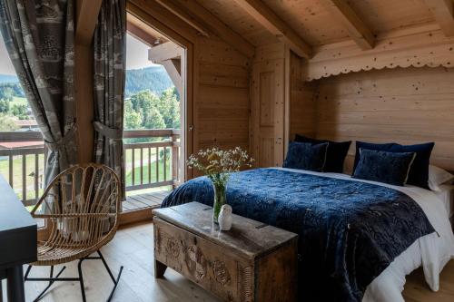 a bedroom with a bed and a large window at Hôtel Les Roches Fleuries in Cordon