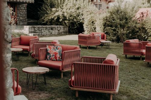 a group of red chairs and tables in the grass at Hôtel Les Roches Fleuries in Cordon