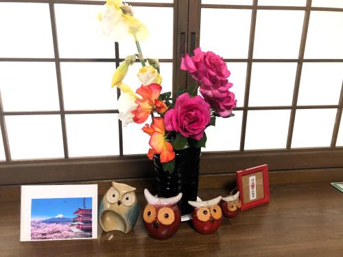 a vase with flowers in it on a table with pictures at フクロウの御宿 春日居館 in Isawa