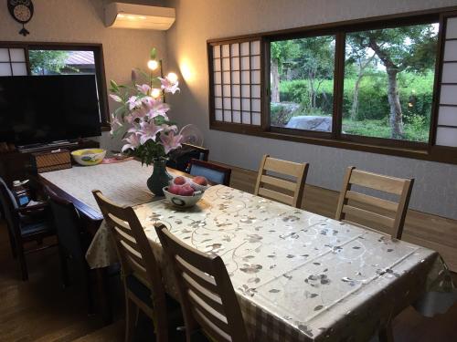 a dining room table with a vase of fruit on it at フクロウの御宿 春日居館 in Isawa