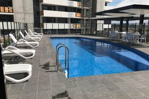 a large swimming pool with white chairs and a building at Liverpool holiday apartment 2Bedroom 2Bathroom in Liverpool