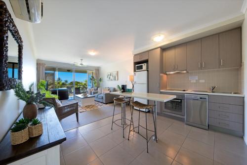 eine Küche und ein Wohnzimmer mit Tisch und Stühlen in der Unterkunft Waterlily - One Bedroom Apartment in Airlie Beach