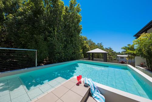 a swimming pool with a red toy sitting next to it at Waterlily - Two Bedroom Apartment in Airlie Beach