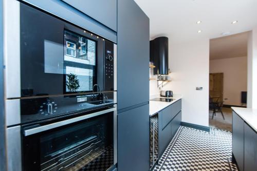 a kitchen with black cabinets and a microwave at Casa Craven by Casa del Artista, 4 Bedroom Designer Home in Skipton