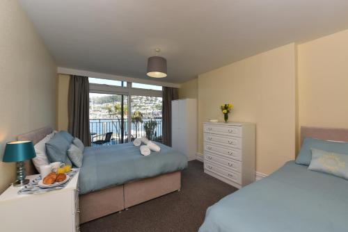 a bedroom with two beds and a dresser and a window at Riverside 1 in Dartmouth