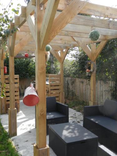 a wooden pergola with two chairs and a table at peaceholm at cromer in Cromer