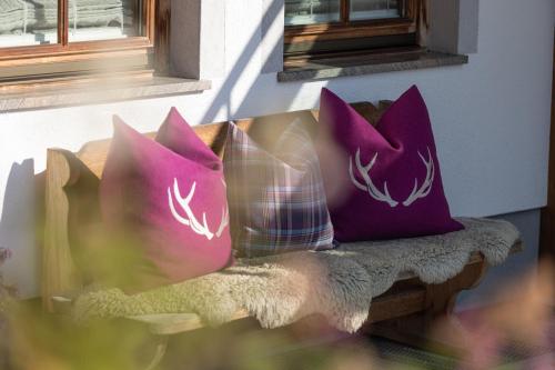 two purple pillows sitting on a bench next to a window at Wellnessappartements Margit in Alpbach