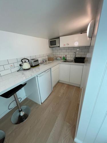a small kitchen with white cabinets and a table at Mount View Overnight Accommodation in Penzance