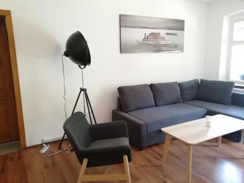 a living room with a blue couch and a chair at Kleine Galerie Apartment für 3 mit Küche Kamin Netflix Parken und Hofladen in Steinhöfel