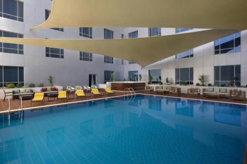 a large swimming pool with chairs and a building at ibis Jeddah City Center in Jeddah