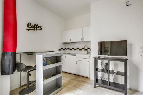 Il comprend une cuisine avec des placards blancs et une télévision. dans l'établissement Le Black and White - Trianon, à Versailles