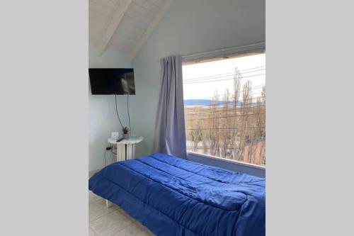 ein Schlafzimmer mit einem blauen Bett und einem Fenster in der Unterkunft MONOAMBIENTE en El Calafate in El Calafate