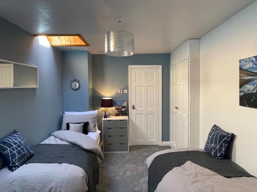 two beds in a room with blue walls at Mynydd A Môr in Trefor