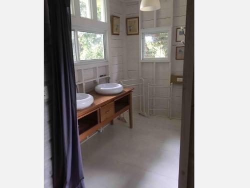 a bathroom with two sinks on a wooden vanity and two windows at Los Secretos Guesthouse in Bocas Town