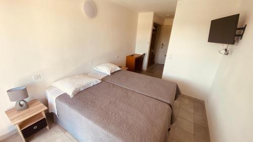 a small bedroom with a bed and a television at Hôtel de la Poste Piscine in Peymeinade