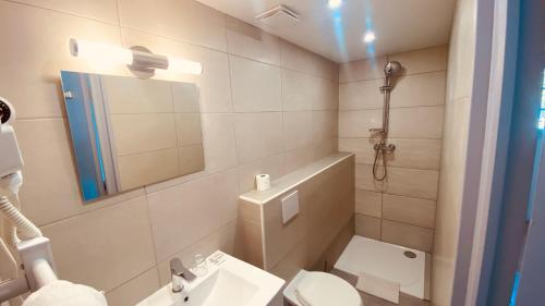 La salle de bains est pourvue de toilettes, d'un lavabo et d'un miroir. dans l'établissement Hotel de la Poste, à Peymeinade