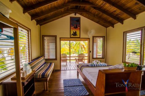 a bedroom with a bed and a couch and windows at Pelican Beach Resort South Water Caye in Dangriga