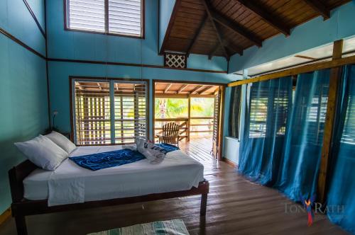 um quarto com uma cama num quarto com janelas em Pelican Beach Resort South Water Caye em Dangriga