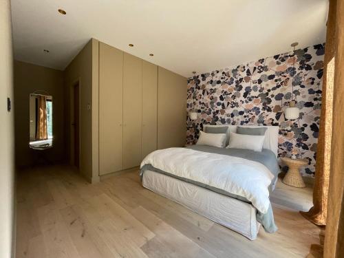 - une chambre avec un lit et un mur aux accents floraux dans l'établissement Les Loges en Provence - Villa Contemporelle, à Pujaut