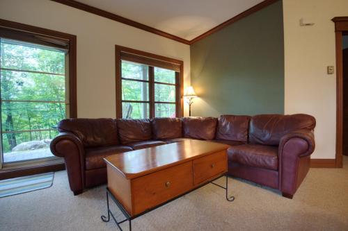 a living room with a brown leather couch and a coffee table at Le Plateau by Rendez-Vous Mont-Tremblant in Mont-Tremblant