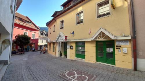 an empty street with a building with green doors at Jasmin dog friendly pension with shared kitchen in the center in Murau