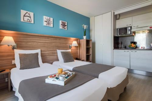 Habitación de hotel con 2 camas y bandeja de comida en Appart’City Confort Vannes, en Vannes