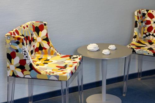 two chairs and a table in a room at Hôtel Le Funi de Cossonay in Cossonay