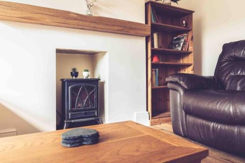 a living room with a leather couch and a fireplace at 3-Bed Cottage-Plymouth-Dog friendly-Sleeps7 in Plymouth