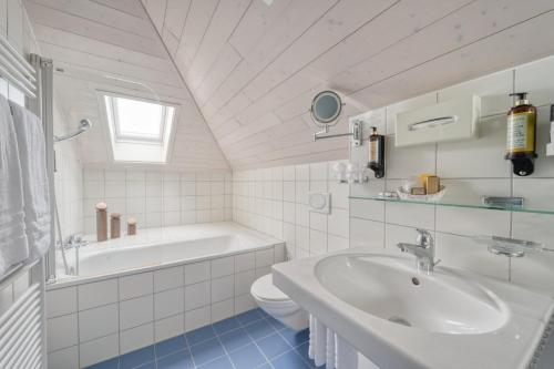 La salle de bains est pourvue d'un lavabo, d'une baignoire et de toilettes. dans l'établissement Hôtel Le Funi de Cossonay, à Cossonay