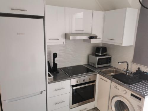 a kitchen with white cabinets and a sink and a microwave at EROS Maisonette in Latchi area just 700 meters or one-minute drive from Polis Municipal Beach in Lachi