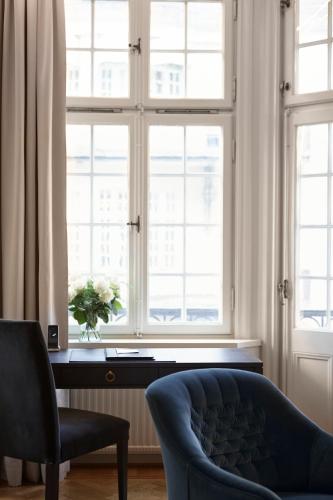 a room with a chair and a desk with windows at Hotel Diplomat Stockholm in Stockholm