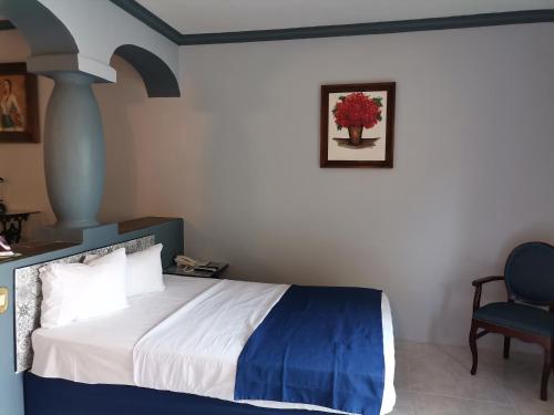 a bedroom with a bed and a blue chair at Gran Hotel Hacienda De La Noria in Aguascalientes