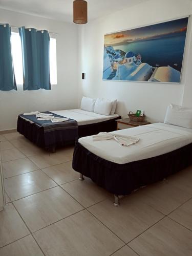 two beds in a room with blue curtains at La Suite Praia Hotel in Caucaia