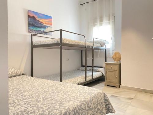 エル・プエルト・デ・サンタマリアにあるApartamento Pasaje Del Marのベッドルーム1室(二段ベッド2台、窓付)が備わります。