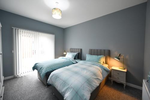 Sunny Shores Cottage في ترون: سريرين في غرفة نوم بجدران زرقاء ونافذة