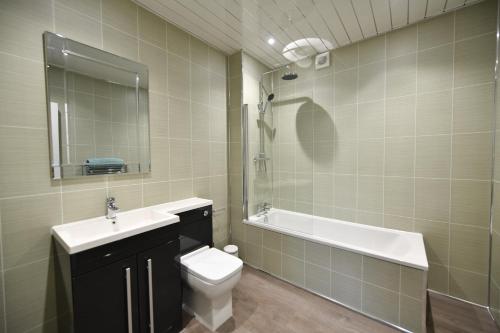 a bathroom with a sink and a toilet and a shower at Sunny Shores Cottage in Troon