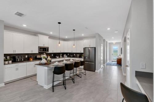 a kitchen with white cabinets and a island with bar stools at Lovely Private Pool Villa wFREE Resort Access in Kissimmee
