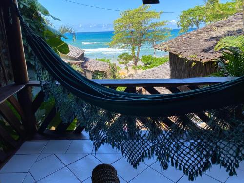 a hammock on a balcony with a view of the ocean at Pousada Hanalei in Itacaré