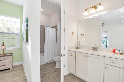 a white bathroom with a sink and a toilet at Margaritaville Cottage, PRIVATE POOL, Near Disney in Orlando