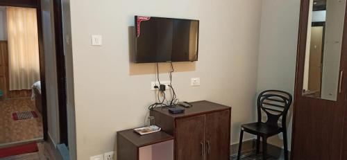 a room with a chair and a television on a wall at Hotel Sonar Tori in Gangtok