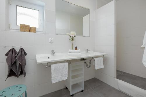 a white bathroom with a sink and a mirror at Baltic Center Bungalows in Sarbinowo