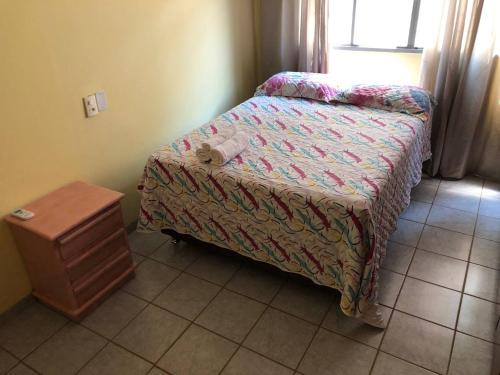 a small bedroom with a bed and a night stand at Oncotô Palmas Hostel in Palmas